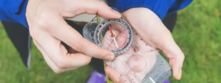 Mini, clear compass being used to find a direction to follow