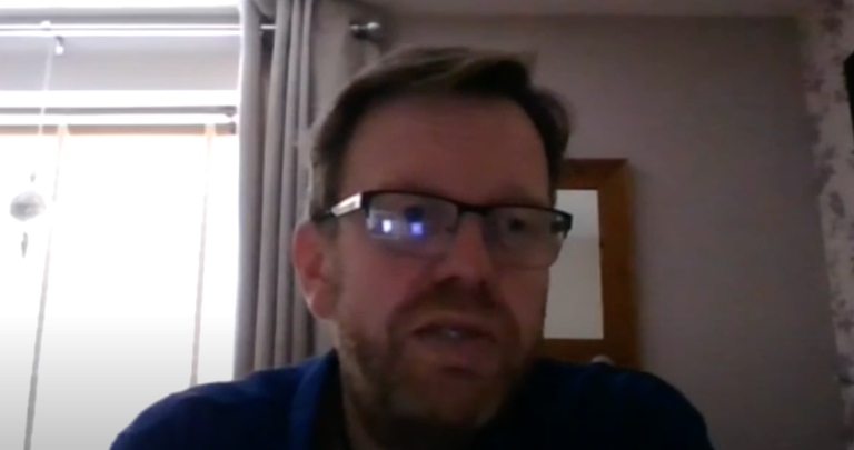 Professional participating in a video call from a home or remote workspace, speaking during an online meeting.