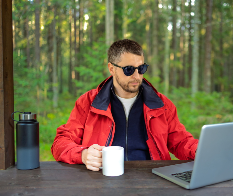 Remote leader working on a laptop in a natural setting, demonstrating how to lead a remote team effectively.
