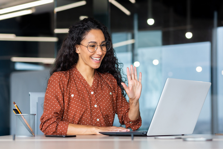Business leader waving on video call while using DiSC to improve remote team communication