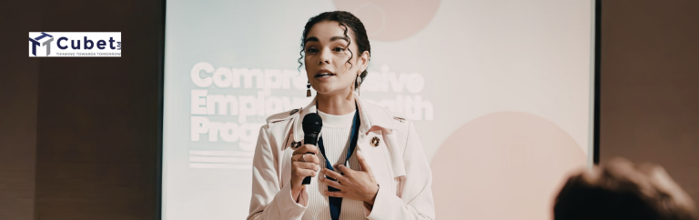 Professional delivering a presentation with a microphone in front of a screen, speaking at a business or corporate event.
